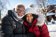 © ribalka yuli - Beautiful elderly heterosexual African American couple in warm jackets hugging, smiling and looking at camera