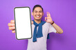 © Bangun Stock Photo - Cheerful young Asian man holding smartphone with blank screen and gesturing okay sign isolated on purple background. Advertising new mobile app, mockup concept