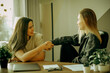 © Raisa Kanareva - Two young female colleagues drink coffee in the office and discuss work