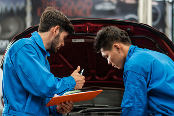 Wall Mural - Auto mechanic checking maintenance checklist while colleague worker repair car at auto garage shop. After service for safety vehicle