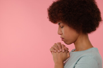 Wall Mural - Woman with clasped hands praying to God on pink background. Space for text