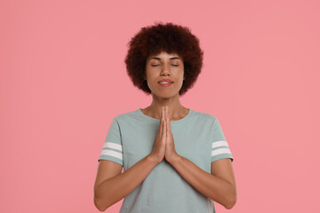 Wall Mural - Woman with clasped hands praying to God on pink background