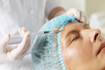 Sticker - Doctor giving facial injection to senior woman in clinic, closeup. Cosmetic surgery