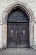 Old decorative wooden entrance door to the church. Large wooden arched gates with carved details, decorative metal elements and handles