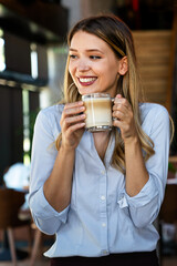 Wall Mural - Portrait of happy young business woman drinking coffee in a break.