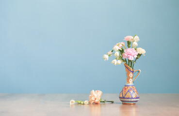 Wall Mural - flowers in vintage jug on wooden table on blue background