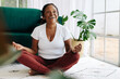 © (JLco) Julia Amaral - Happy senior woman meditating in lotus position at home