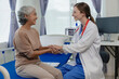 © ArLawKa - Female doctor with clipboard talking with elderly female patient at hospital Senior woman or doctor with digital tablet Consult or plan treatment to treat medical professionals with female patients.