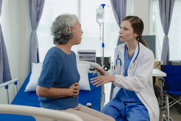 Female doctor with clipboard talking with elderly female patient at hospital Senior woman or doctor with digital tablet Consult or plan treatment to treat medical professionals with female patients.