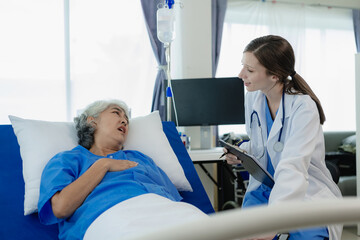 Female doctor with clipboard talking with elderly female patient at hospital Senior woman or doctor with digital tablet Consult or plan treatment to treat medical professionals with female patients.