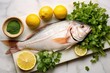fresh raw whole fish with sliced lemons and cilantro on a marble slab