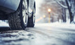 canvas print picture - Low angle view of a car tire on a winter road covered in ice and snow. Winter travel background