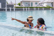 © Ekkasit A Siam - close friends two multiethnic, African woman and Hispanic standing in water Drinking wine in pool and chatting happily. Wear a swimsuit Wear a hat and sunglasses in the pool on hot sunny days.