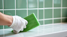 Hand in a rubber glove sponges the tiles in the bathroom. Creative concept of house cleaning, tile cleaner. Copy space.