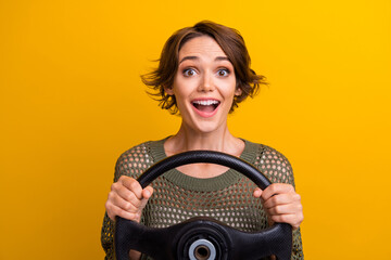 Poster - Photo portrait of lovely young lady hold excited steering wheel wear trendy knitwear khaki garment isolated on yellow color background