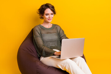 Poster - Photo of lovely charming girl wear trendy clothes sitting pouf watching video film isolated on yellow color background