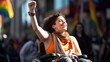 A lady sitting in a wheelchair is raising her arms and shouting loudly on the street, celebrating a victory in her political advocacy.