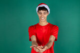 Fototapeta  - Chico vestido de papa noel en navidad mostrando con sus manos. hombre de rojo y blanco sobre fondo verde