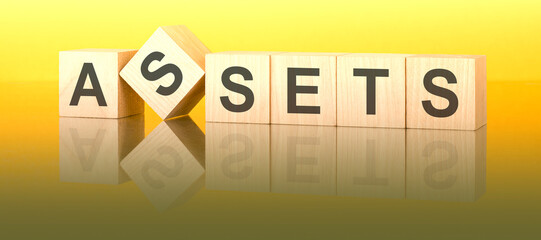 Sticker - assets text on wooden blocks on a yellow table. light background