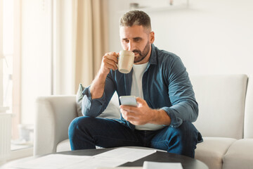 Poster - man using smartphone while managing paperwork and drinking coffee indoor