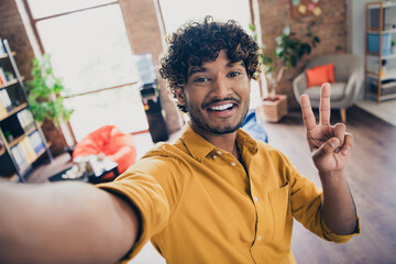 Poster - Photo portrait of young male wear yellow shirt selfie photo showing v-sign interior loft industrial style