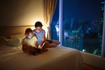 Poster - Child and mother read a book in dark room.