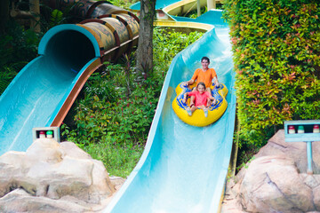 Wall Mural - Kids on water slide. Family in aqua theme park.