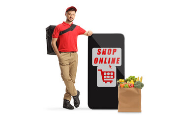 Wall Mural - Delivery guy leaning on a smartphone and a grocery bag, online shopping concept