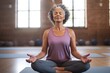 © Adriana - Smiling Mature black woman meditating sitting in a yoga studio