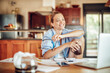 © Geber86 - Happy young woman using her laptop in the kitchen at home