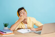 Attractive smiling teenager boy wearing casual clothes yawning sitting at desk using laptop