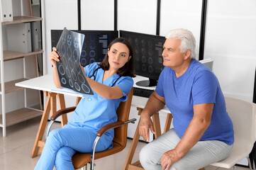 Sticker - Female doctor showing x-ray scan to senior patient in medical office