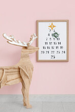 Wooden Reindeer And Christmas Calendar On Pink Wall In Room