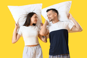 Wall Mural - Young couple with pillows on yellow background