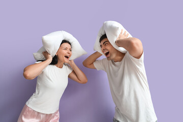 Wall Mural - Young couple with pillows shouting on lilac background