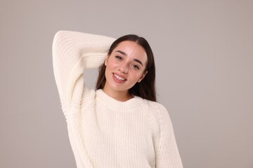 Wall Mural - Beautiful young woman in stylish warm sweater on grey background
