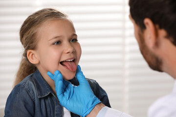 Canvas Print - Doctor in medical glove examining girl`s oral cavity indoors