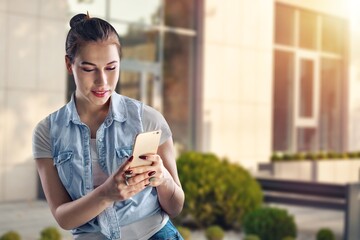 Poster - Pretty woman use smartphone against building.