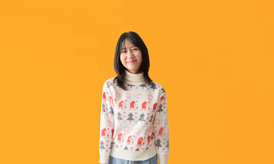 Wall Mural - Cheerful young Asian teenager girl wearing a Christmas sweater, Happy smiling standing Looking posing, isolated on yellow background