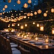 Shot of a long dining table setup outdoor beneath a string of glowing lanterns, stock photography
