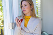 © WavebreakMediaMicro - Happy caucasian woman standing with tea by window and looking ahead in sunny room at home