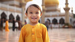 a southeast asian boy aged 3 year old wears a turmeric muslim clothes, in the background is a mosque. He looks happy 