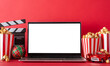Winter staycation: side view of laptop, popcorn, baubles, movie clapper, and a tiny delivery car on a tabletop, red wall backdrop for advertising. Enjoy streaming movies at home during the holidays