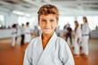 Portrait of handsome young boy in his karate kimono training in a gymnasium, asian martial art training indoor, karate group class