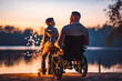 Young father with disability on a wheelchair with his son right beside him with sunset in the background, spending quality time together