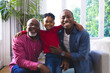 © Wavebreak Media - Portrait of happy african american father, son and grandson embracing on couch at home, copy space