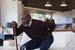 © Wavebreak Media - Pained african american senior man with walking stick standing up from couch at home holding back