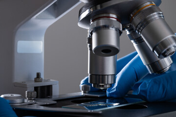 Poster - Close up of hand in glove using laboratory microscope and copy space on white background