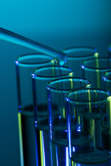 Poster - Vertical image of close up of laboratory test tubes and pipette with copy space on blue background