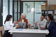 © kiattisak - Four busy office workers listen to an African team leader take part in a group meeting in the office room. American supervisor gives advice to multi-ethnic company employees Consulting concept